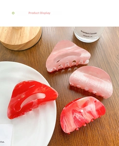 Detailed view of four acetate hair claws with marble textures and glitter on a wooden table