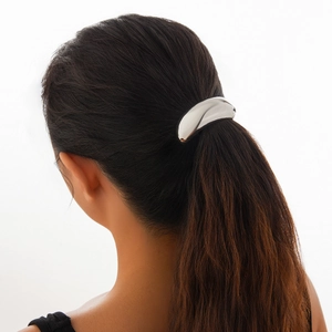 Close-up of a minimalist silver metallic ponytail cuff with a sleek mirror finish surface