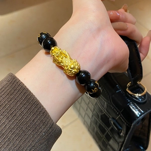 Macro detail of obsidian bead bracelet with golden Pixiu and Buddhist mantra carvings