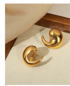 Detail of gold teardrop earrings with smooth mirror finish on a minimalist display