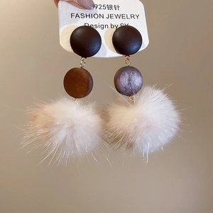 Detail of 925 silver stud earrings with dark brown wood disc and soft beige fur ball