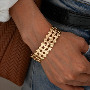 Detailed view of the layered oval hollow grid bangle with a polished gold finish