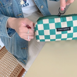 Detail of green and beige checkered corduroy pencil case with circular zipper pull