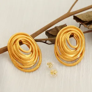 Golden spiral hoop earrings in stacked circular design on white textured fabric