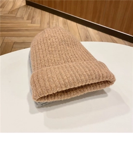 Dettaglio di un berretto in maglia morbida ed elastica marrone chiaro con trama grigia calda