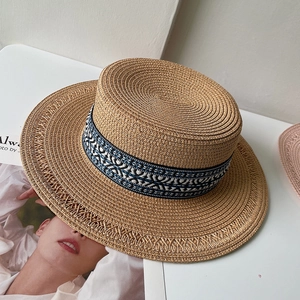 Dettaglio della trama in paglia e nastro con motivo geometrico blu su questo cappello boater