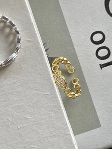 Detailed view of an 18K gold adjustable ring with pavé zircon oval on textured card