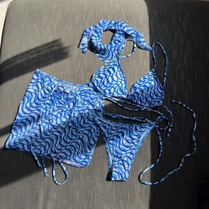 Detailed flat lay of blue wave print bikini set with matching sarong and headband