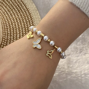 Handgefertigtes Perlenarmband mit goldenen Schmetterlingsanhängern am Handgelenk