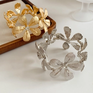 Detail von gold- und silberfarbenen Blumenarmbändern mit Kristall und Netztextur