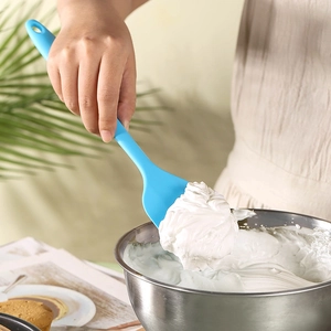 Blue large silicone spatula mixing white cream in a bowl for cake baking and cooking