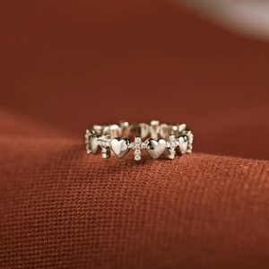Macro shot of silver ring with alternating heart and diamond cross patterns