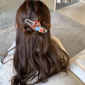 Detail of cute brown fabric puppy hair clip worn on long wavy hair in a cozy setting