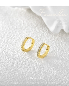 Macro shot of gold hoop earrings with pavé set white zircon stones on white texture