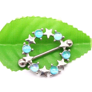 Macro shot of silver stainless steel nipple ring with blue opal stones and stars on a leaf