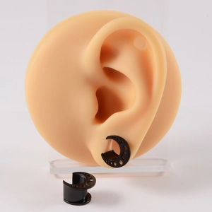 Detail of black moon-shaped ear gauge expander on a silicone ear model showcase