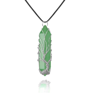 Detail of handmade wire-wrapped tree of life pendant on a green crystal hexagonal pillar