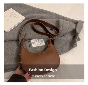 Dettagli della borsa a mezzaluna in pelle marrone con rivetti dorati su cappotto