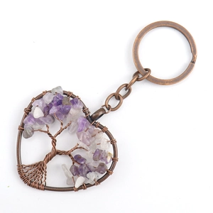 Macro detail of heart keychain with bronze tree of life and purple crystal stones