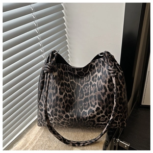 Detailed view of leopard print tote bag with knotted strap design and shadow lighting
