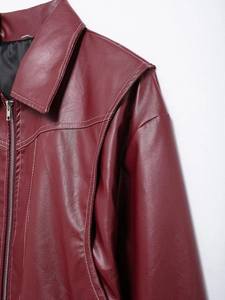 Detail of burgundy leather jacket featuring white contrast stitching and metal zipper