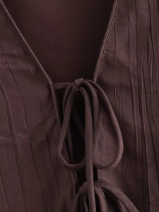 Détail du tissu plissé marron foncé avec élégant col en V et fermeture à nouer