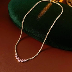Detail of gold zircon necklace with pink gemstones on premium velvet display box