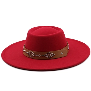 Detail view of red wool fedora hat featuring a brown leather strap with metal rivets
