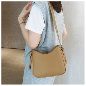 Détail du sac sous le bras en similicuir marron avec pompons décoratifs et surpiqûres