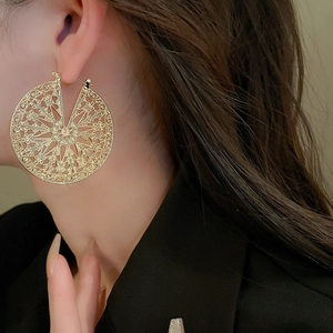 Gros plan de boucles d'oreilles dorées vintage avec motif ajouré sur un mannequin