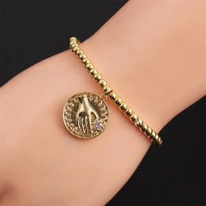 Detail of gold beaded bracelet featuring a palm coin pendant with a crystal stone