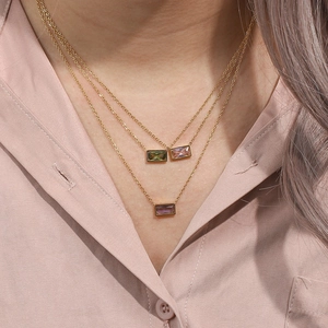 Detailed close-up of 18K gold-plated layered necklaces featuring three colored gemstones