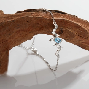 Detailed view of silver pulse heartbeat chain featuring a blue oval gemstone on wood