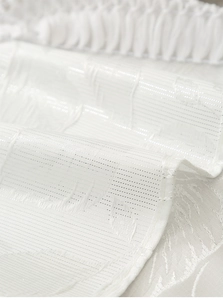 Macro shot of white woven fabric showing detailed jacquard texture and glitter patterns