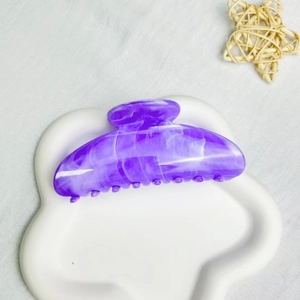 Close-up of purple marble patterned acetate hair claw clip on white decorative plate