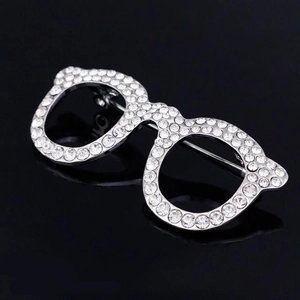 Detailed view of silver glasses brooch with sparkling rhinestones on black background