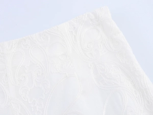 Detailed macro shot of delicate white paisley embroidery on high-quality cotton fabric
