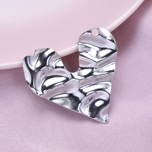 Macro shot of silver 304 stainless steel heart pendant with irregular rippled texture