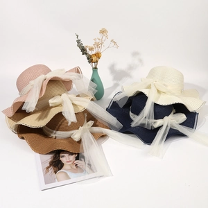 Detail of straw sun hats with elegant mesh bow and pearl accents in multiple colors