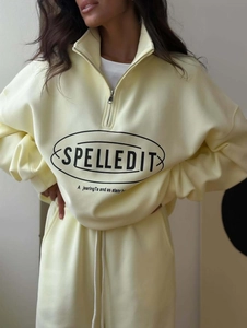 Detail of light yellow tracksuit featuring half-zip collar and Spelledit chest print