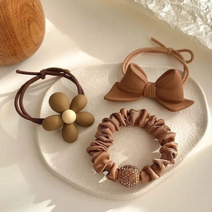 Three-piece earth tone hair accessory set with matte bow and satin scrunchie on a tray