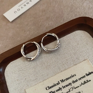 Close-up of silver double-hoop earrings with twisted texture and zircon inlay on tray