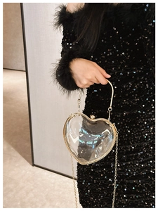 Detail of transparent heart acrylic bag with gold metal frame and stylish chain strap