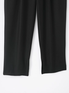 Gros plan sur la texture en sergé noir et la fente latérale au bas du pantalon femme