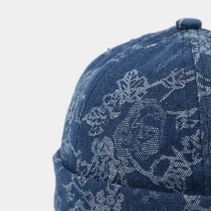 Detailed close-up of dark blue denim miki hat featuring white floral and skull patterns