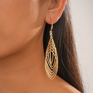 Detail of gold layered teardrop earrings with textured hollow design on model