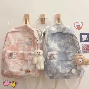 Detailed view of canvas backpack with tie-dye patterns, cute cartoon patches, and plush charms
