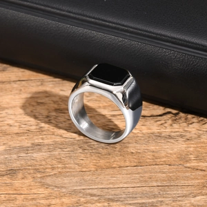 Detailed view of men's silver stainless steel ring with square black stone on wood