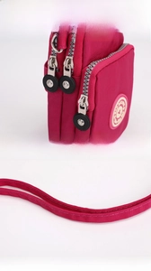 Detail of rose red nylon crossbody bag showing three-layer zippers and star logo