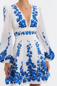 Detailed view of the deep V-neck and blue floral orchid pattern on white fabric